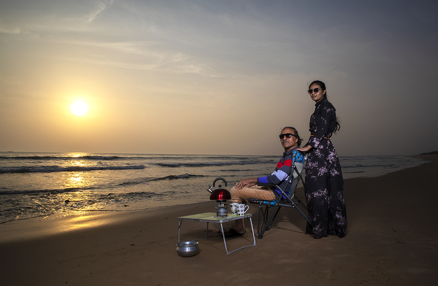 a couple enjoying luxury camping with caravan, campervan, vanlife, motorhome for unique experience of overlanding outdoor holidays away from tourists crowd to relax unwind quiet silent secluded location at pong dam in himachal hp india.