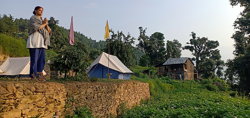 a single traveler woman enjoying yoga and meditation in barot valley with caravan motorhome campervan in himachal for offbeat nomadic camp for holiday with social distancing.