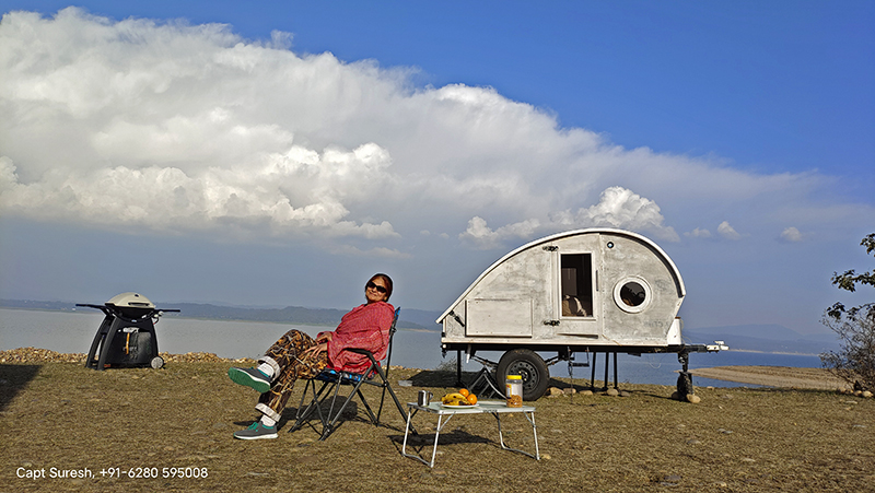 single woman enjoying vacation staying onboard teardrop trailer at offbeat locations with caravan RV recreational vehicle with campervan nomadic experience himachal pradesh.