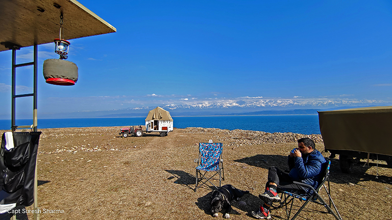 guest enjoying morning tea in our camp of rental caravan campervan available on rent for offbeat locations around Pong Dam, family holidays, nomadic unique experience rural himachal pradesh india.