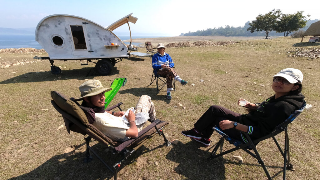 family enjoying camping with caravan motorhome campervan around pong dam reservoir in himachal for an offbeat experience of outdoor nomadic overlanding hygienic camp holiday away from tourists to relax and unwind corona safe india.