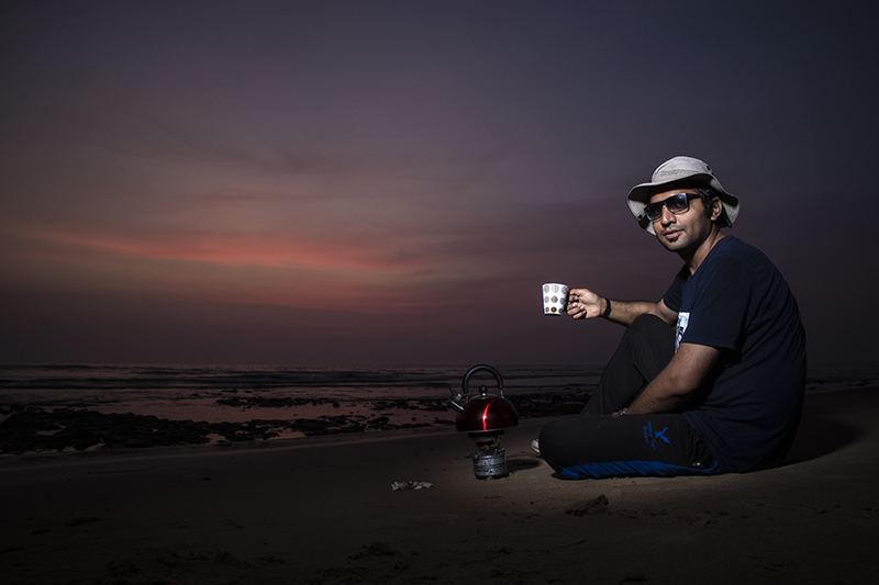 a guest enjoying tea and offbeat family holidays at in wilderness with caravan RV recreational vehicle campervan overland truck nomadic unique experience pong dam himachal.